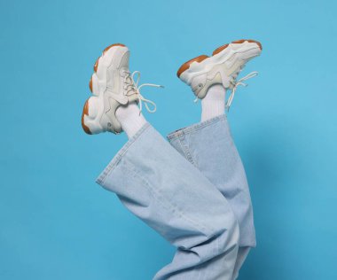 Açık mavi arka planda şık ayakkabılar giyen kadın, yakın plan.