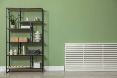 Salon içinde zeytin duvarının yanında farklı dekorasyonu olan ahşap raf ünitesi.