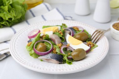 Ringa balıklı lezzetli salata, yumurta, hardal ve sebzeler beyaz fayanslı masada, yakın plan.