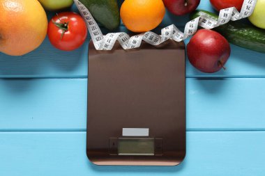 Elektronik mutfak ölçeği, mezura ve açık mavi ahşap masa üzerindeki ürünler, düz yatak. Diyet