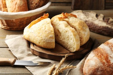 Farklı somunlar taze ekmek, bıçak ve çiviler ahşap masada, yakın plan