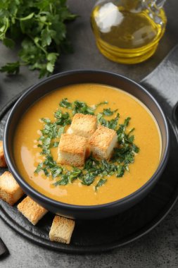 Lezzetli mercimek kremalı çorba. Gri masada kızarmış ekmek var. Yakın plan.