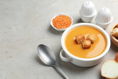 Açık gri masada kızarmış ekmeklerle servis edilen leziz mercimek kremalı çorba, yakın plan. Metin için boşluk