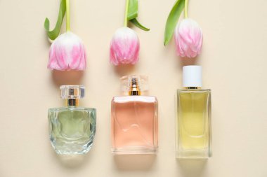 Parfüm şişeleri ve bej arka planda güzel çiçekler.
