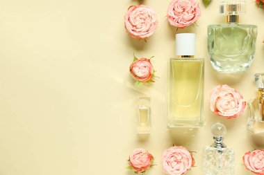Parfüm şişeleri ve bej arka planda güzel çiçekler. Metin için boşluk