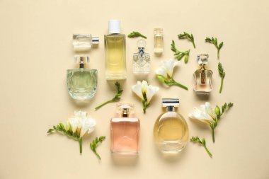 Parfüm şişeleri ve bej arka planda güzel çiçekler.