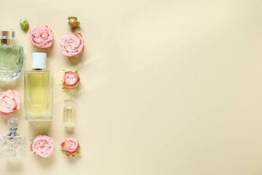 Parfüm şişeleri ve bej arka planda güzel çiçekler. Metin için boşluk