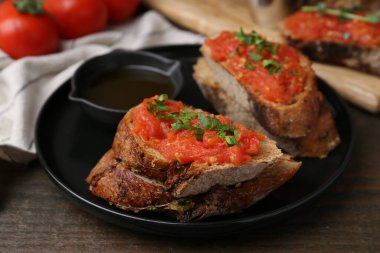 Domatesli lezzetli ekmek, maydanoz ve yağ ahşap masada, yakın plan.