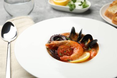 Gri masada servis edilen lezzetli deniz ürünleri çorbası, yakın plan.