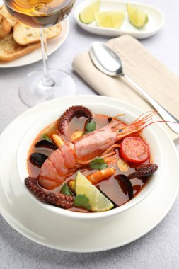 Açık gri masada servis edilen lezzetli deniz ürünleri çorbası, yakın plan.