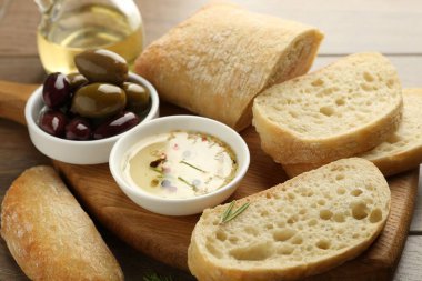 Ahşap masada yağlı, zeytinli ve baharatlı dilimlenmiş ekmek, yakın plan.