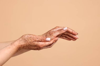 Bej arka planda ellerini ovuşturan kadın, yakın plan.