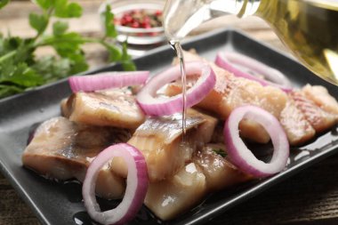 Ringa balığının parçalarına yağ dökerek, ahşap masada soğan dökerek.