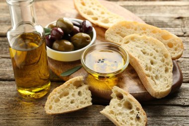 Yağlı ekmek dilimleri, ahşap masada baharatlar ve zeytinler, yakın plan.
