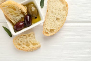 Beyaz ahşap masa üzerinde yağlı ve zeytinli dilimler, düz yatıyordu.