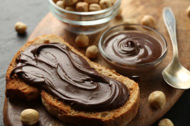 Çikolata kaplı bir dilim ekmek ve masada fındık, yakın plan.