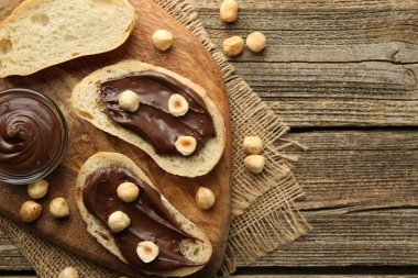 Çikolata sürülmüş ekmek dilimleri ve ahşap masada fındıklar, düz yatak. Metin için boşluk