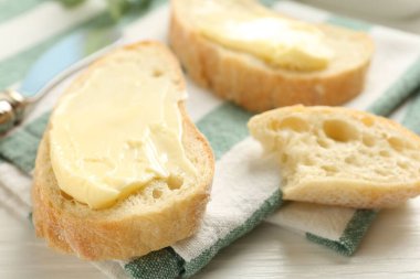 Beyaz ahşap masada tereyağlı ekmek dilimleri, yakın plan.