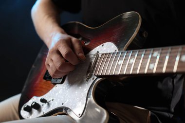 Siyah arkaplanda gitar çalan adam, yakın plan