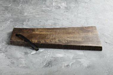 Açık gri desenli bir masada ahşap servis tahtası, yakın plan. Metin için boşluk