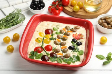 Çiğ Focaccia, sebzeli, zeytinli ve baharatlı beyaz ahşap masa, yakın plan.