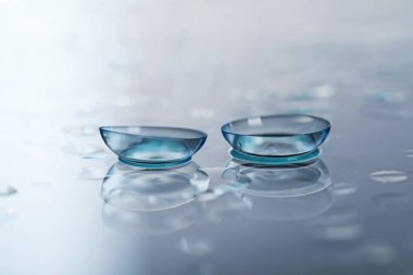 Renkli ayna yüzeyine kontak lens ve su damlaları, yakın plan.