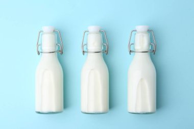 Açık mavi zemin üzerinde taze süt şişeleri, düz yatıyordu.