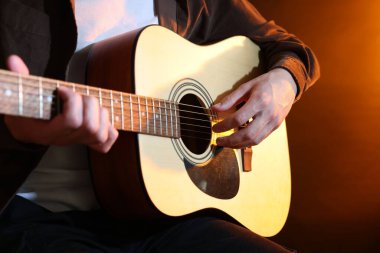 Kahverengi arka planda gitar çalan adam, yakın plan.