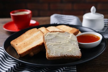 Tahta masaya tereyağlı ve reçelli lezzetli ekmek dilimleri, yakın plan.