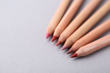 Açık gri arka planda pek çok farklı dudak kalemi, yakın plan. Metin için boşluk