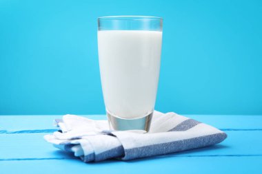 Açık mavi ahşap masada cam içinde taze süt.