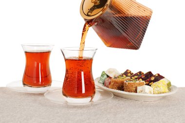 Masadaki cam fincana sıcak Türk çayı dökülüyor, beyaz arka plan, yakın plan