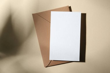 Bej arka planda boş tebrik kartı ve kağıt zarf, üst görünüm