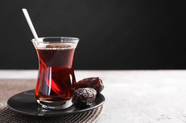 Geleneksel cam fincanda Türk çayı ve açık gri masada tarihler, yakın plan. Metin için boşluk