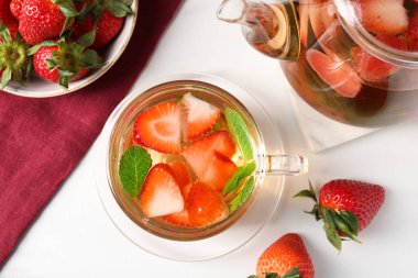 Aromatik çilekli meyve çayı ve beyaz masada nane şekeri.