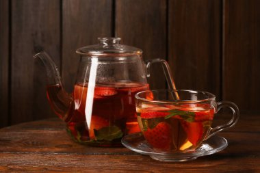Aromatik çilekli meyve çayı ve ahşap masada nane şekeri.