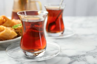 Lezzetli Türk çayı, beyaz mermer masada şekerlerle servis edilir, yakın plan.