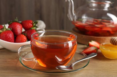 Çilekli Aromatik meyve çayı ve ahşap masada bal, yakın plan.