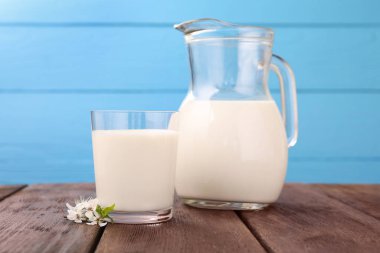 Taze süt ve çiçekler ahşap masada açık mavi arka planda, yakın plan