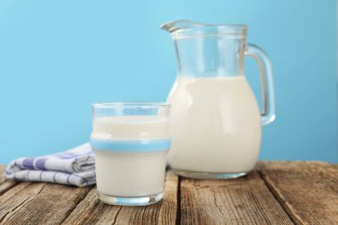 Açık mavi arka planda, ahşap masada taze süt, yakın plan.