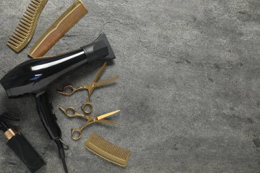 Gri dokulu arka planda farklı saç şekillendirme araçları, düz yatış. Metin için boşluk