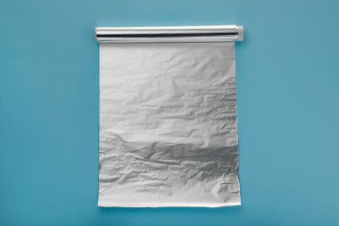 Açık mavi arkaplanda alüminyum folyo rulosu, üst görünüm