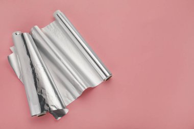 Pembe arka planda alüminyum folyo ruloları, üst manzara. Metin için boşluk