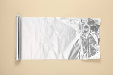 Bej arkaplanda alüminyum folyo rulosu, üst görünüm