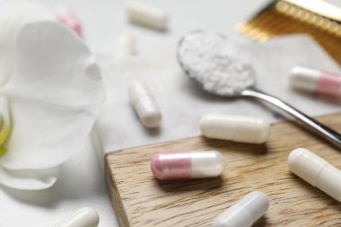 Kolajen kapsülleri, toz ve çiçek beyaz masada, yakın plan.