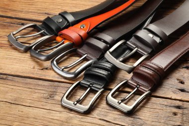 Ahşap masada birçok farklı deri kemer, yakın plan.