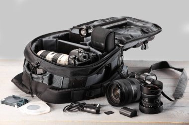 Profesyonel fotoğrafçının ekipmanı ve sırt çantası açık ahşap masada.