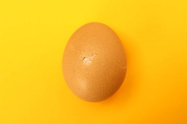 Turuncu arka planda kırık kabuklu bir yumurta, üst manzara.