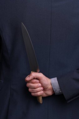Sırtında bıçak tutan bir iş adamı, yakın plan.
