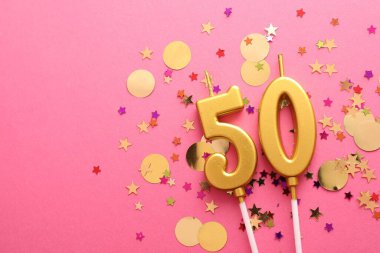 50. yaş günü. Pembe arka planda mumlar ve konfetiler var. Metin için boşluk
